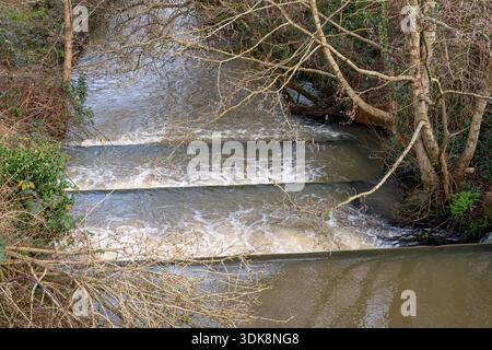 Wasserfall oder Kaskade auf einem schnell fließenden Bach oder Fluss nach starkem Regen, Fluss gefüllt mit Hochwasser, das in Kaskade oder Wasserfall stürzt. Stockfoto