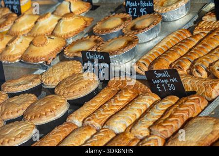 Verschiedene frisch gebackene Kuchen und Brötchen werden im Fenster einer Bäckerei im Stadtzentrum von Southampton, Hampshire, England, Großbritannien, ausgestellt Stockfoto