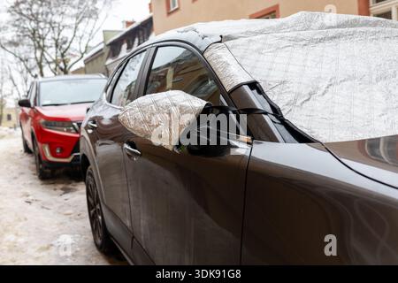 Windschutzscheibe und Seitenspiegel des Fahrzeugs mit Wärmeschutzabdeckung. Winter-Autozubehör, das Frost, Eis und Schnee verhindert und hält Stockfoto