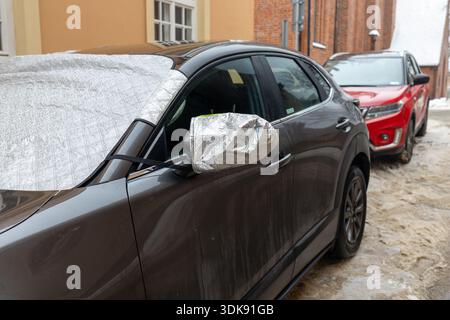 Windschutzscheibe und Seitenspiegel des Fahrzeugs mit Wärmeschutzabdeckung. Winter-Autozubehör, das Frost, Eis und Schnee verhindert und hält Stockfoto
