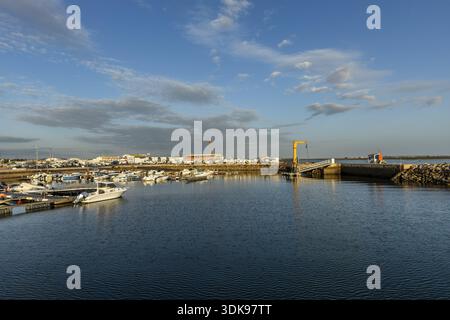 Großer Panoramablick auf den Yachthafen und den Hafen in Olhao, Algarve, Portugal. Kleine Boote liegen auf ruhigem blauem Wasser nahe der Hafeneinfahrt, mit po Stockfoto