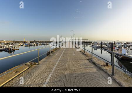 Großer Panoramablick auf den Yachthafen und den Hafen in Olhao, Algarve, Portugal. Kleine Boote liegen auf ruhigem blauem Wasser nahe der Hafeneinfahrt, mit po Stockfoto