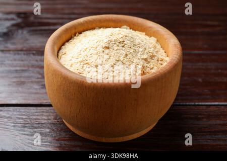 Trockene Hefeflocken in Schüssel auf Holztisch, Großaufnahme Stockfoto