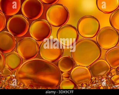 Eine Nahaufnahme goldener Ölblasen in einer warmen Orange-Palette mit runden Formen, glatten Oberflächen und durchscheinender Tiefe. Perfekt für abstrakte Hintergründe Stockfoto