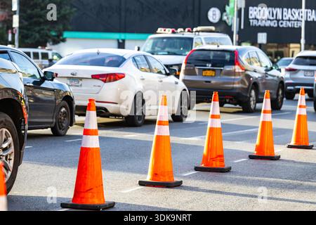 Verkehrskegel blockieren Fahrspuren auf einer belebten Stadtstraße mit Autos und Stadtverkehr tagsüber Stockfoto