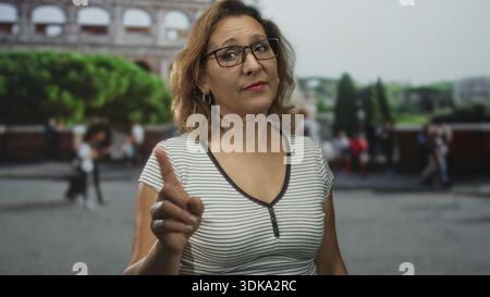Frau zeigt mit dem Finger auf die Kamera im kolosseum Gebäude im Freien, Touristenattraktion in der Nähe römischer Ruinen; Warnbehörde. Stockfoto