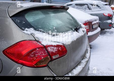 Schneebedecktes Auto hinten mit eisigem Fenster und Rücklicht auf dem Parkplatz Stockfoto