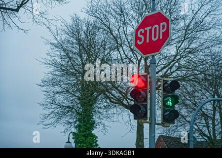 Eine Ampelanlage trägt oben ein Stoppschild, ein Kopf ist rot, der andere grün, was einen Moment kontrollierter Überquerung und erfasst Stockfoto