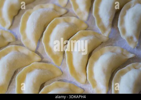 Die Klöße sind reihenweise auf einer Ebenen Oberfläche angeordnet, die zum Kochen bereit ist. Dies zeigt den Prozess der Zubereitung von Mahlzeiten zu Hause. Stockfoto