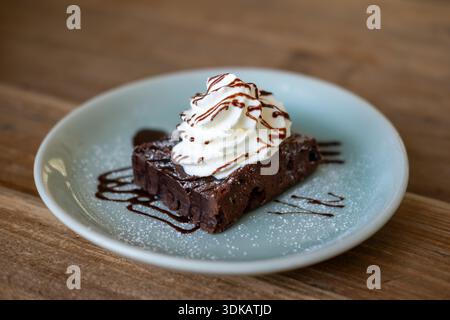 Nahaufnahme von Brownie mit Schlagsahne und Schokoladensauce Stockfoto