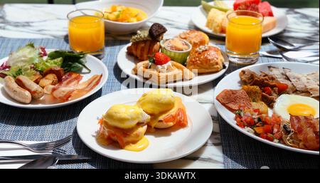 Frühstück mit Eiern benedict, Gebäck und frischem Orangensaft auf Marmortisch. Luxuriöses Hotelrestaurant, morgendlicher Lifestyle und Gourmet Stockfoto