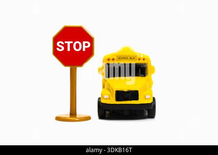 Schulbus Miniatur neben einem roten Stoppschild auf weißem Hintergrund Stockfoto