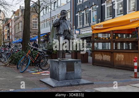 Bronzestatue des Sängers Andre Hazes auf einem Sockel in Amsterdam. Straßenszene mit Fahrrädern, Cafés und typisch holländischer Backsteinarchitektur in de Pijp. Am Stockfoto