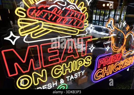 Neonbeschriftungen, die Fleisch auf Pommes frites und gebratenes Hühnchen in einem Restaurant in Auckland, Neuseeland, anzeigen. Stockfoto