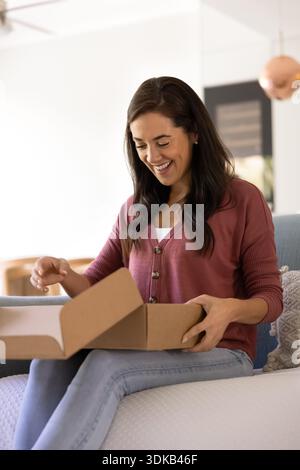 Aufgeregte Frau, die zu Hause das Lieferpaket auspackt Stockfoto