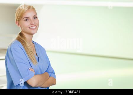Weibliche Krankenschwester, die im Krankenhausflur steht, trägt blaue Peelings neben Metallgeländer, Kopierraum. Kliniker, Gesundheitswesen, Flur, Klinik, Profi Stockfoto