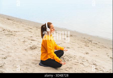 Hochwinkelansicht einer achtsamen Frau, die in der Herbstsaison am Fluss meditiert. Stockfoto