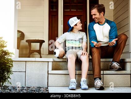 Fußball, Outdoor und Vater mit Kind zum Binden, Sport oder Gespräch zusammen. Happy, redet und Dad mit dem Jungen auf Treppen im Hinterhof für Stockfoto