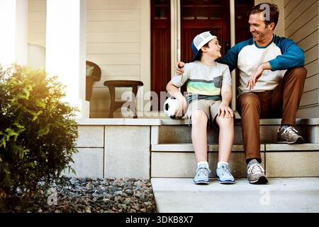 Fußball, Outdoor und Vater mit Kind zum Binden, Sport oder Konversation. Glücklich, redet und Vater mit Kind auf Treppen im Hinterhof für Stockfoto