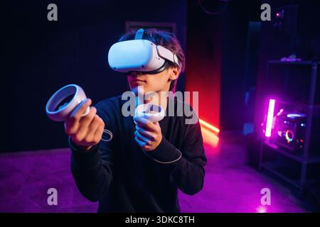 Der junge Mann sitzt drinnen in einer Virtual-Reality-Brille. Stockfoto