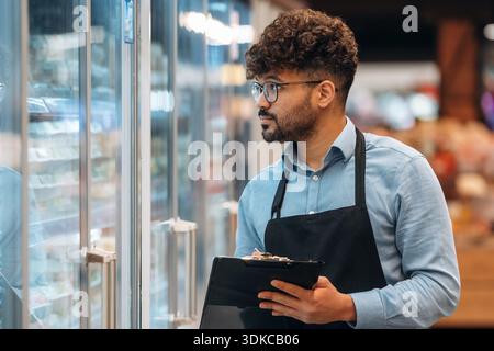 Mit Notizblock. Männlicher Arbeiter ist im Supermarkt. Stockfoto