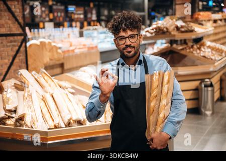 Frische Bäckerei. Männlicher Arbeiter ist im Supermarkt. Stockfoto
