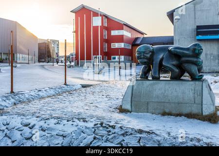 Moderne Inuit-Skulptur auf einem verschneiten urbanen platz, umgeben von zeitgenössischer Architektur, die kulturelle Identität und Winteratmosphäre in der einfängt Stockfoto