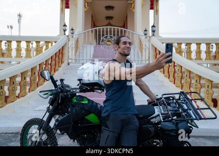 Ein Mann, der Selfie mit dem Abenteuer-Motorrad im Tempel thailands macht Stockfoto