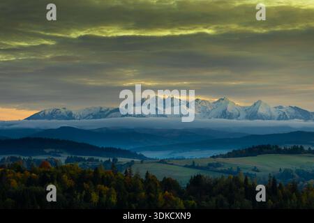 Panoramablick auf das schneebedeckte Tatra-Gebirge bei Sonnenuntergang mit dramatischen Wolken und überlagerten Hügeln im Vordergrund in Südpolen. Stockfoto
