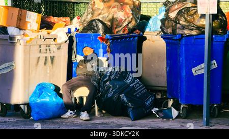 Izmir, Türkei. 30. Januar 2026. Eine junge Person, die auf einem Stuhl vor überfüllten Mülltonnen auf einer Straße der Stadt schläft. Die Szene fängt Momente der Erschöpfung und Erholung inmitten von städtischem Abfall und Verschmutzung ein Credit: İdil Toffolo/Alamy Live News Stockfoto