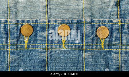Denim-Detail mit sichtbaren Nähten, gelben Nähten und drei Messingknöpfen Stockfoto