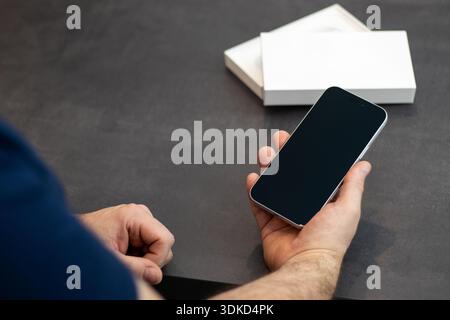 Nahaufnahme eines Mannes, der ein neues Telefon mit schwarzem Bildschirm hält Stockfoto