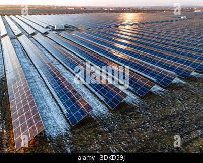 Luftaufnahme eines ausgedehnten Solarkraftwerks mit langen Reihen von Photovoltaik-Panels auf freiem Land. Erzeugung erneuerbarer Energie und sauberer Elektrizität Stockfoto