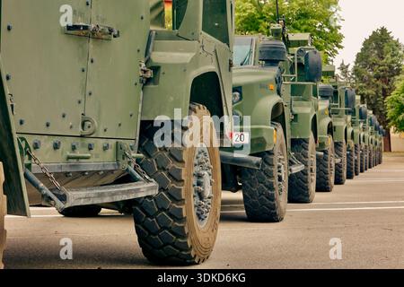 Reihe gepanzerter militärischer Einsatzfahrzeuge, die in Formation auf einem Militärgelände geparkt sind Stockfoto