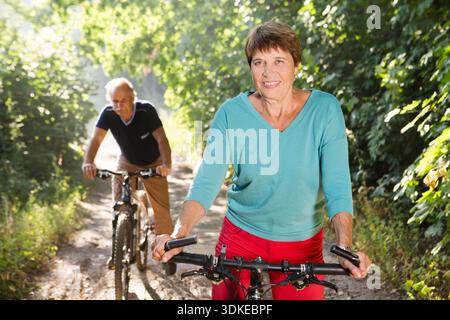 Glückliches Seniorenpaar Fahrt mit dem Fahrrad im Park || Model veröffentlicht Stockfoto