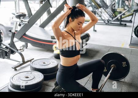 Fixieren der Haare. Die schöne Frau ist im Fitnessstudio. Stockfoto