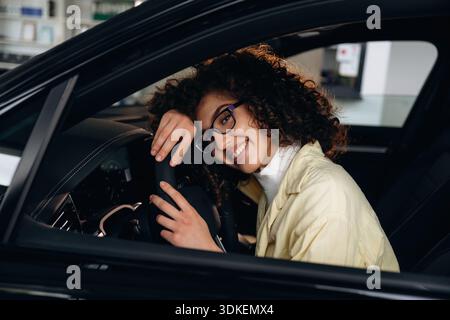 Sich gut fühlen, sitzen und lächeln. Glückliche Frau sitzt im Auto. Stockfoto