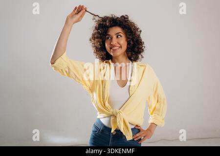 Spiel mit lockigem Haar. Die schöne Frau ist im Studio. Stockfoto