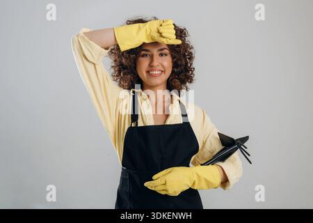 Sie wischt sich die Stirn ab, müde vom Putzen. Die schöne Frau ist im Studio. Stockfoto