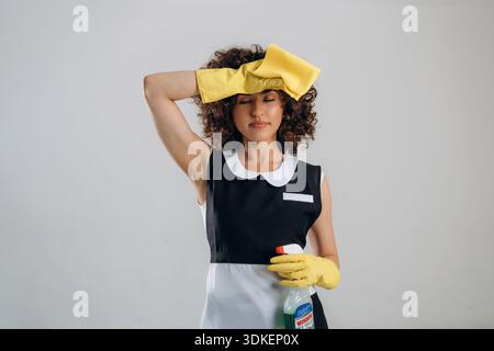 Sie wischt sich die Stirn ab, müde vom Putzen. Die schöne Frau ist im Studio. Stockfoto