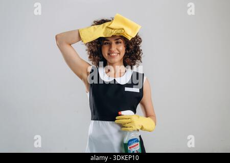 Sie wischt sich die Stirn ab, müde vom Putzen. Die schöne Frau ist im Studio. Stockfoto