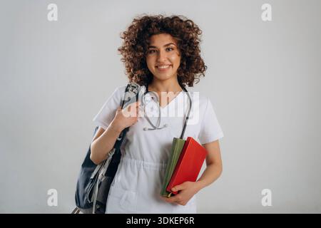 Rucksack und Schulungsmaterial. Die schöne Studentin der Ärztin ist im Studio. Stockfoto