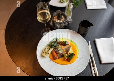 Aus nächster Nähe ein Gourmet-Fischgericht mit dekorativer goldener Zierde, serviert in einem gehobenen Restaurant. Stockfoto