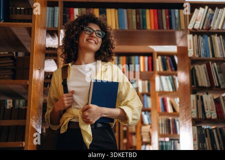 Das Buch halten. Die schöne Frau ist in der Bibliothek. Stockfoto