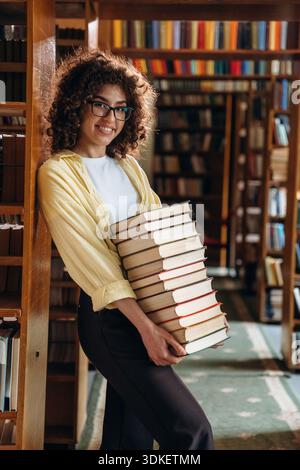 Blick von der Seite, mit vielen Büchern. Die schöne Frau ist in der Bibliothek. Stockfoto