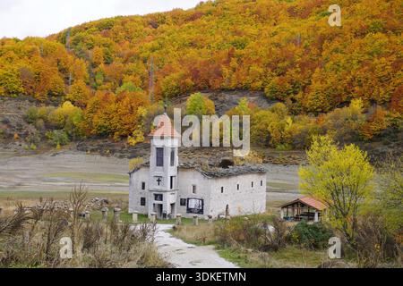 Alte Nikolaikirche in der Nähe des Mavrovo-Sees, Nordmakedonien, teilweise in der Vergangenheit untergetaucht, umgeben von Herbstbäumen, mit Innen- und Außenansicht Stockfoto