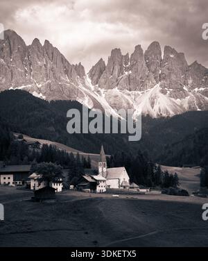 Ein sepiafarbenes Foto zeigt das malerische Dorf Santa Magdalena in den Dolomiten, Italien. Die ikonische Kirche mit ihrem unverwechselbaren Turm Stockfoto