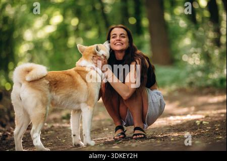 Glückliche Frau ist mit Shiba Inu Hund im Wald. Stockfoto