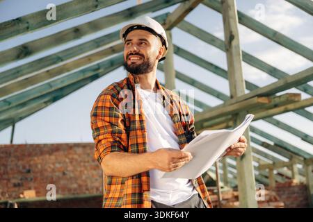Projektmanager ist mit Plan. Bauarbeiter ist auf dem Dach eines Hauses. Stockfoto