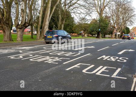 Fahrspuren für Lebensmittelgeschäfte und Tankstellen, die auf der Oberfläche einer Straße oder Autobahn an der Zufahrt zu einem Einzelhandelsgeschäft und einer Tankstelle in Newport, IOW, markiert sind. Stockfoto